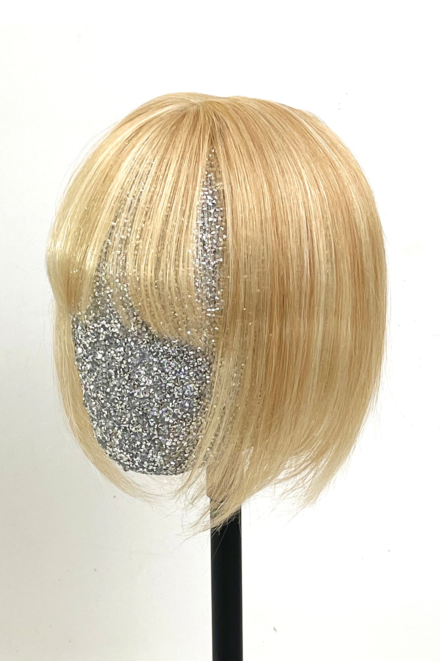 A handmade human hair topper with bangs, displayed on a mannequin head, featuring warm blonde color with highlights.