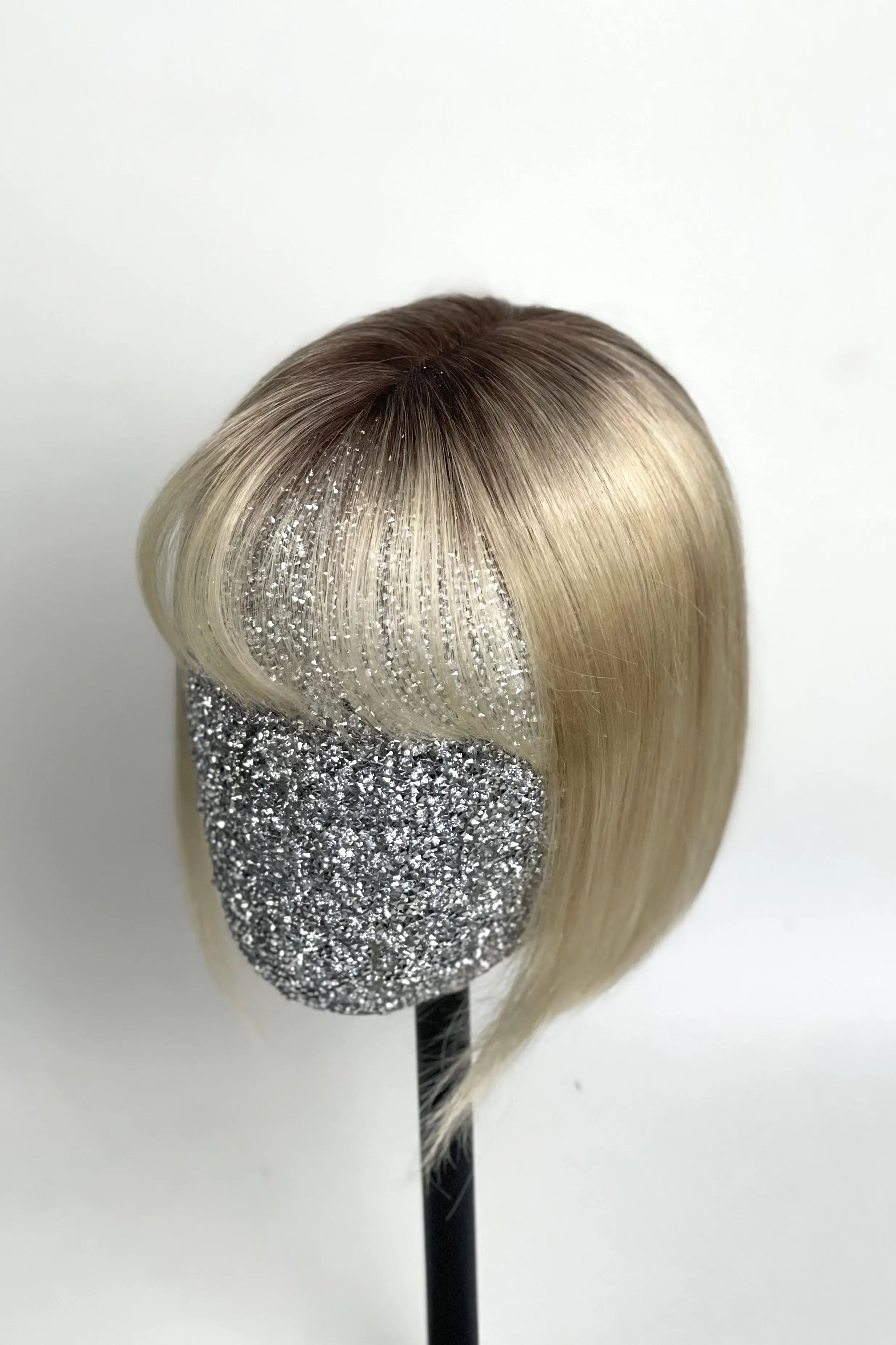 A mannequin head showcasing a light blonde human hair topper with integrated bangs.