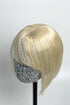 A light blonde human hair topper with bangs displayed on a mannequin head, featuring a sparkly barrette in the forehead area.