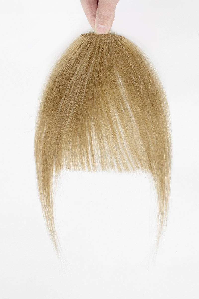Dark Blonde hair extension held by a hand on a white background