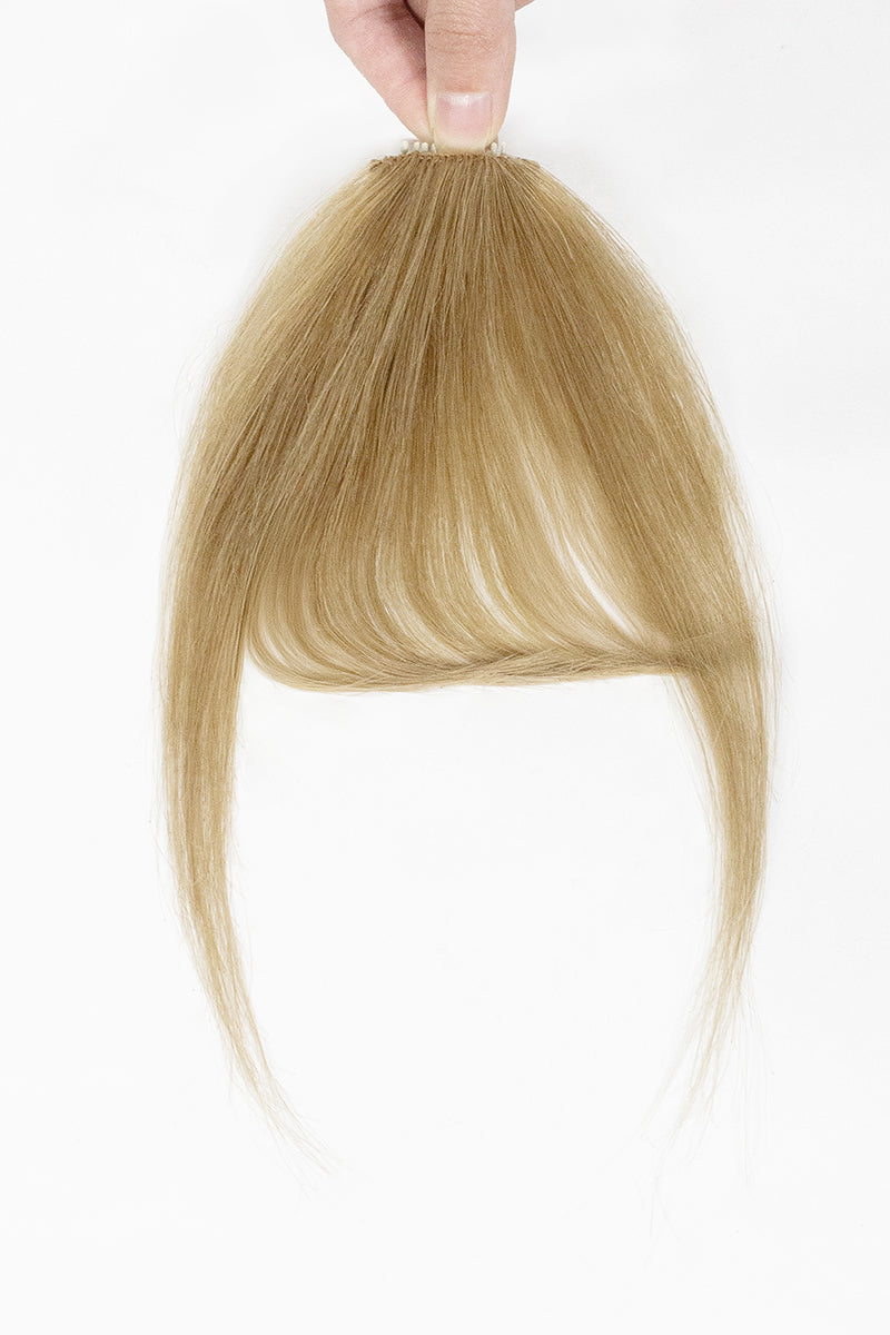 Dark Blonde hair extension held by a hand on a white background