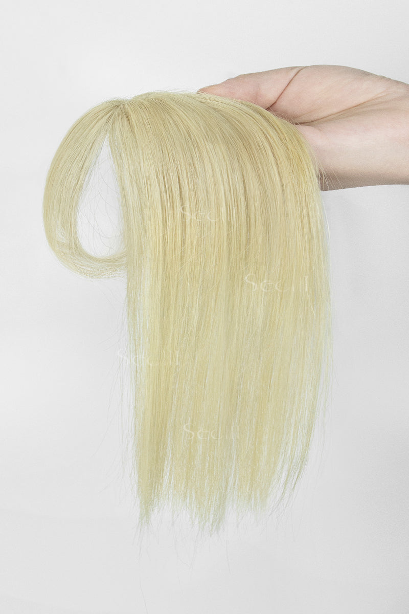 A hand holding a long, straight blonde hair extension or wig piece against a plain white background.
