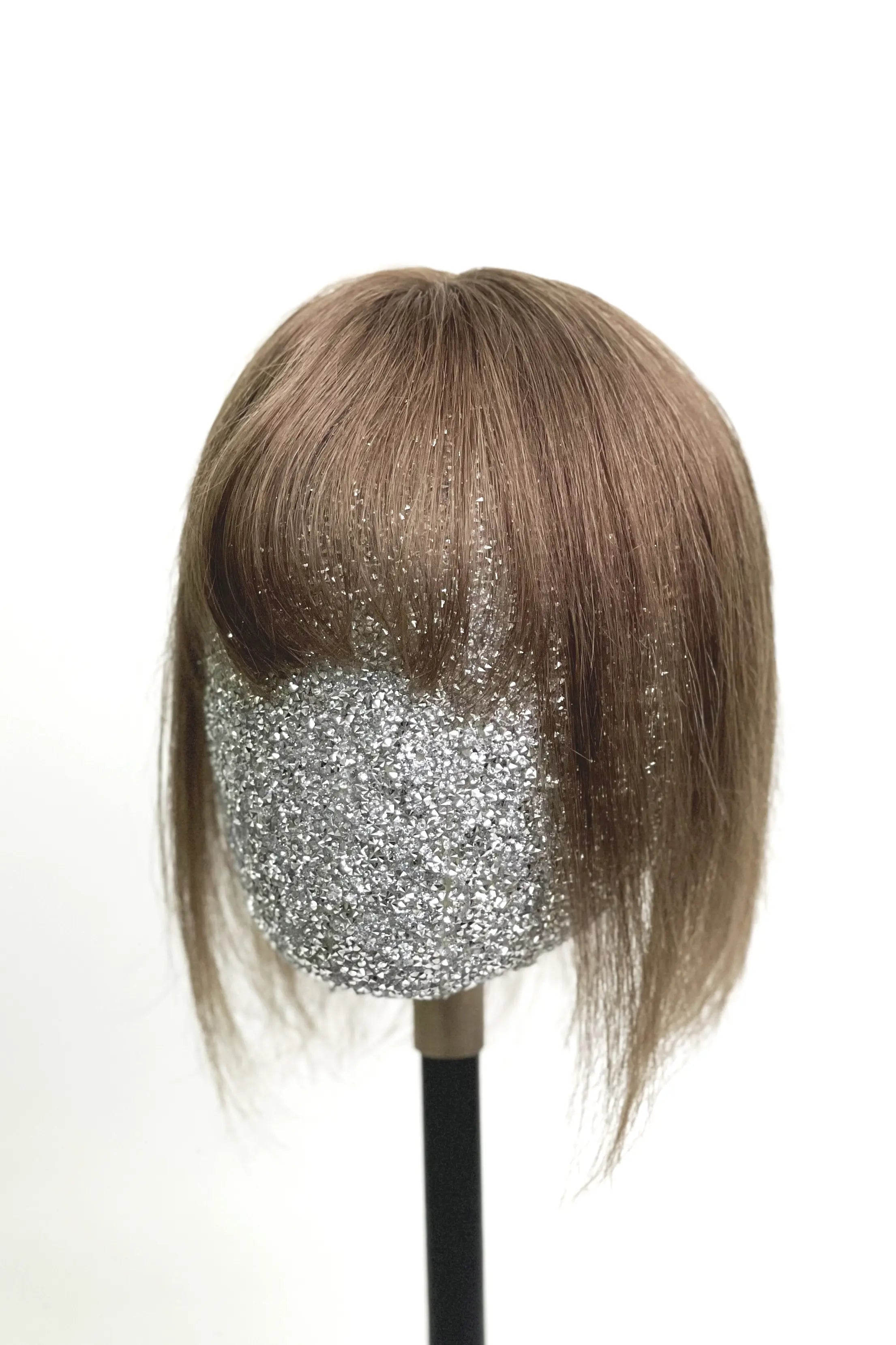 A mannequin head showcasing a medium ash brown human hair topper with bangs.
