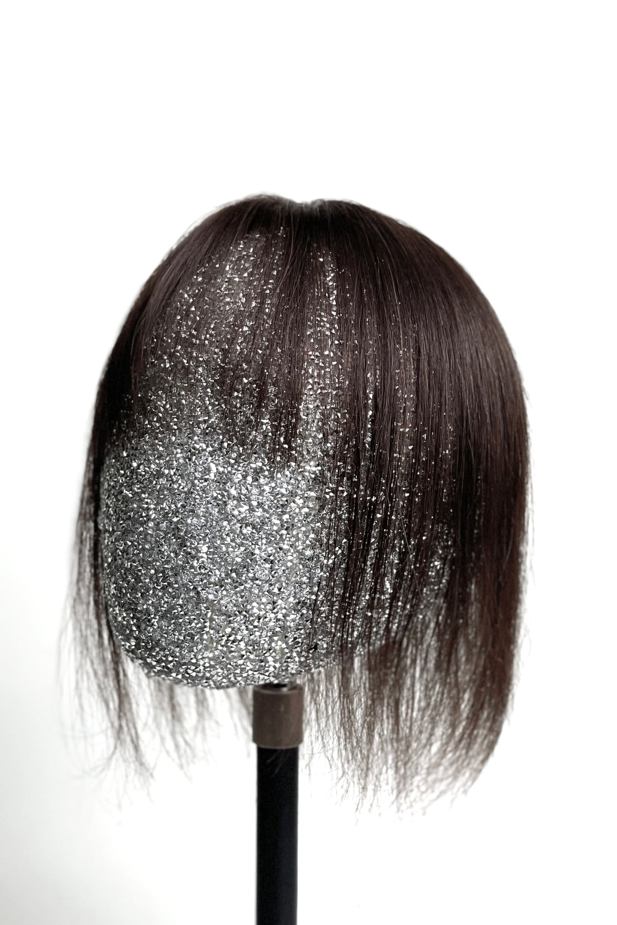 A mannequin head showcasing a dark brown human hair topper with integrated bangs.