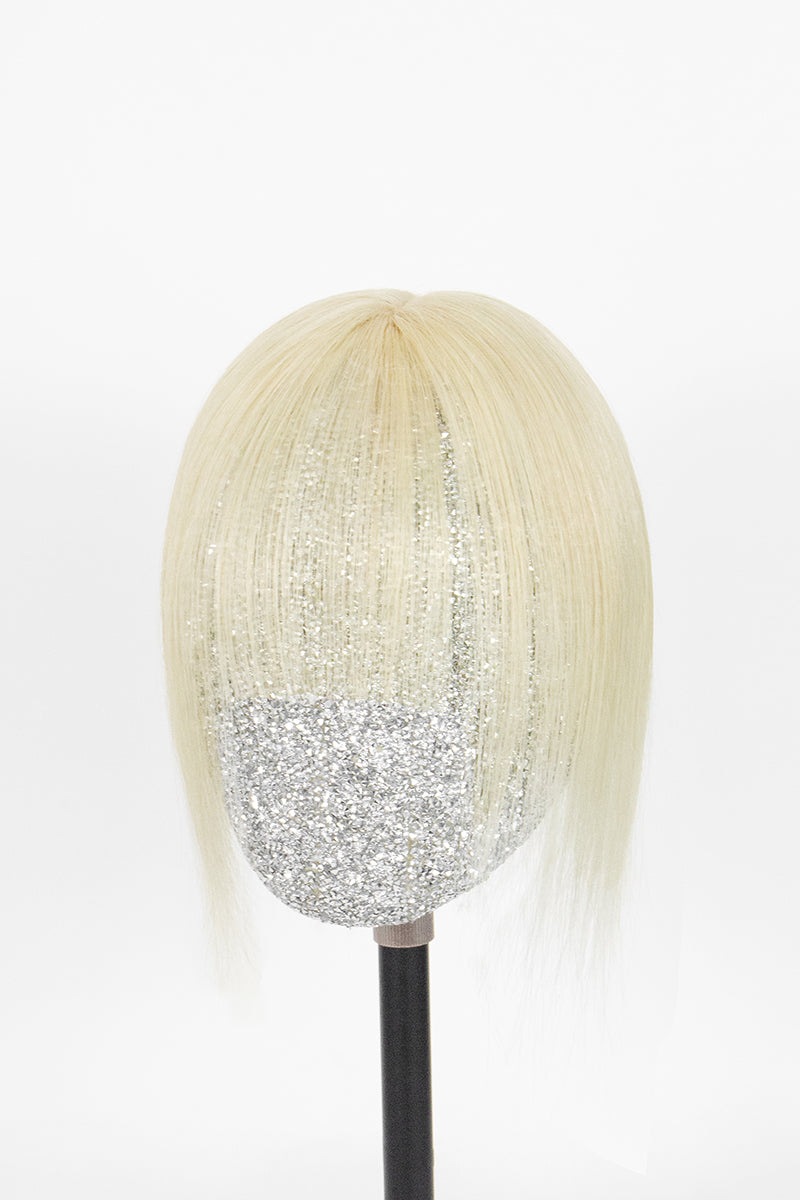 A short, straight blonde wig with bangs displayed on a mannequin head with a black stand against a plain white background.
