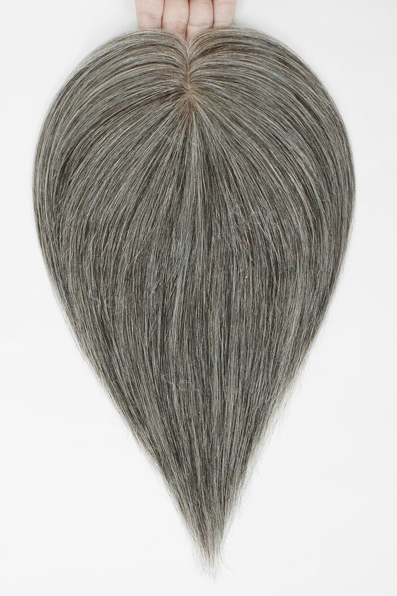 Hand holding a medium grey hair topper with a center part and straight tapered ends.