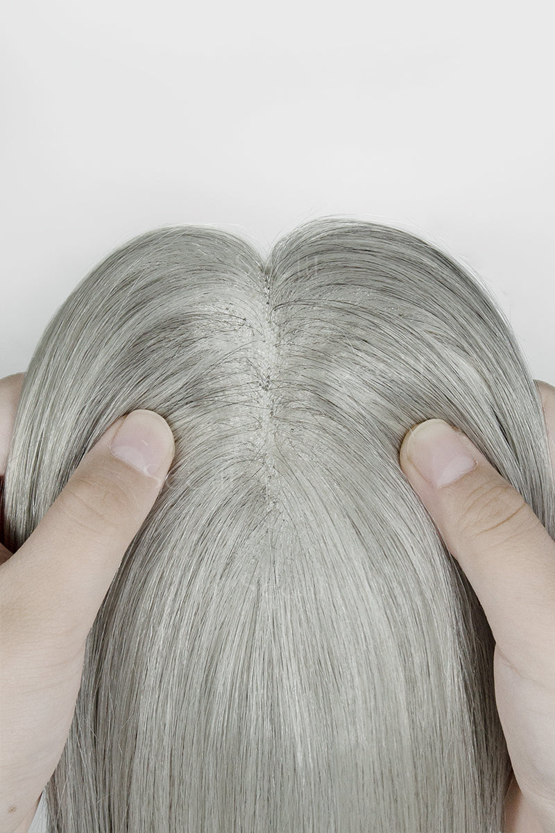 Close-up of a person holding Light Grey hair topper strands against a white background
