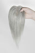 Light Gray hair topper held by a hand against a white background