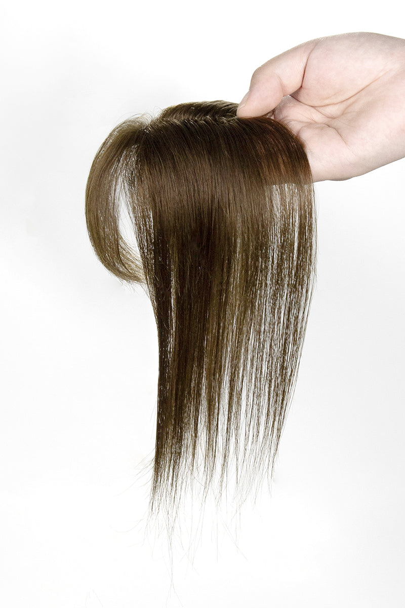 Hair topper held by a hand against a white background
