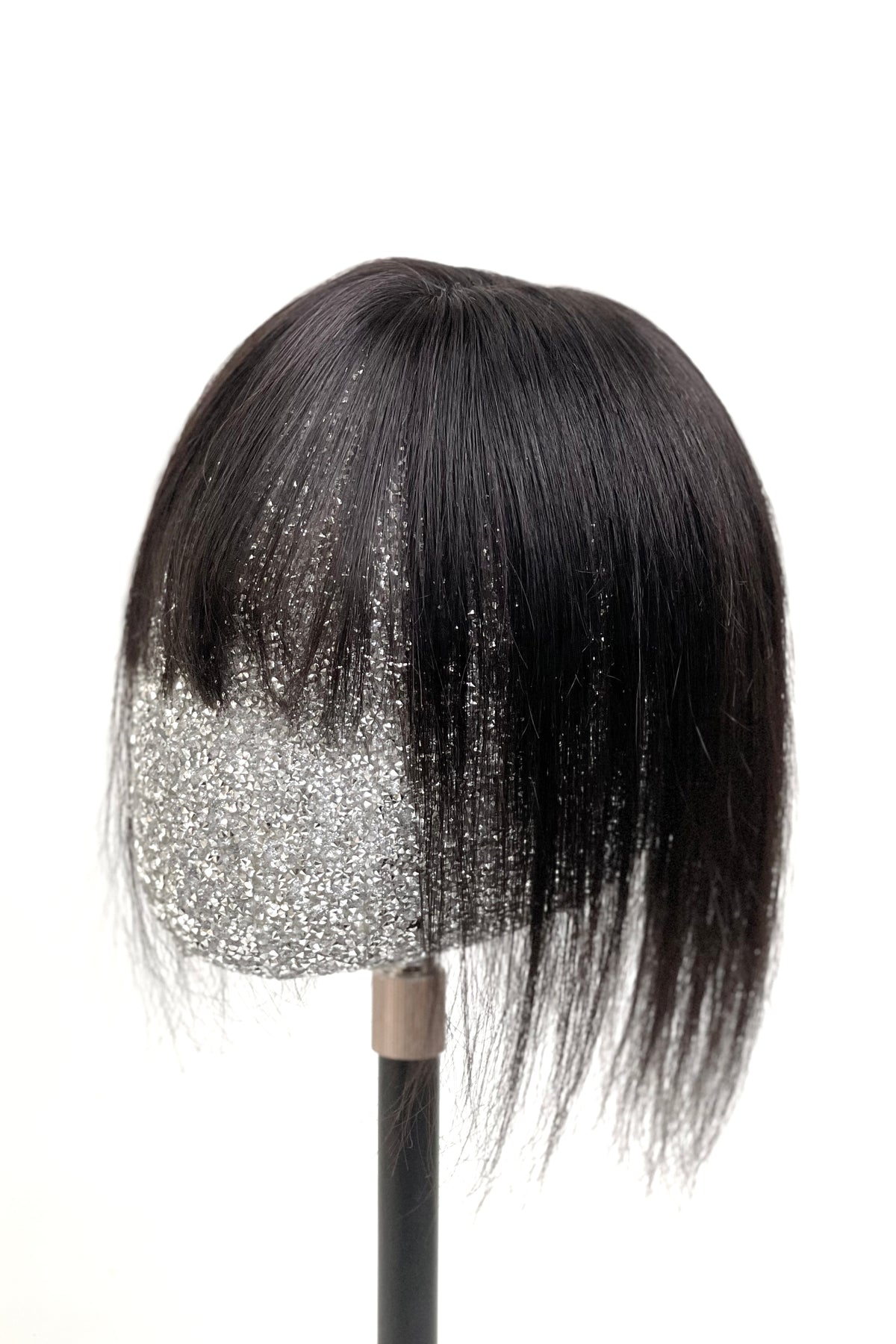 A mannequin head showcasing a natural black human hair topper with bangs.