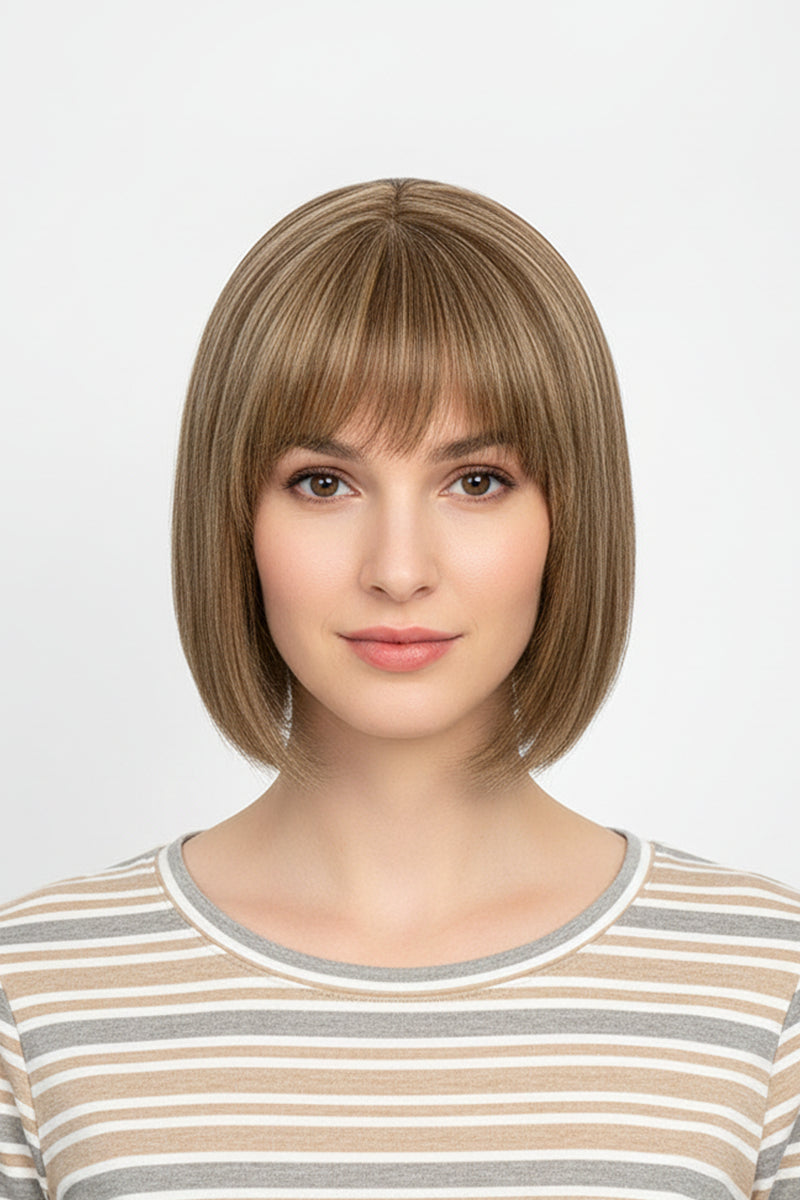 Woman wearing a sandy blonde short bob wig with straight bangs, front view, striped top, light gray background