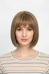 Woman wearing a sandy blonde short bob wig with straight bangs, front view, striped top, light gray background
