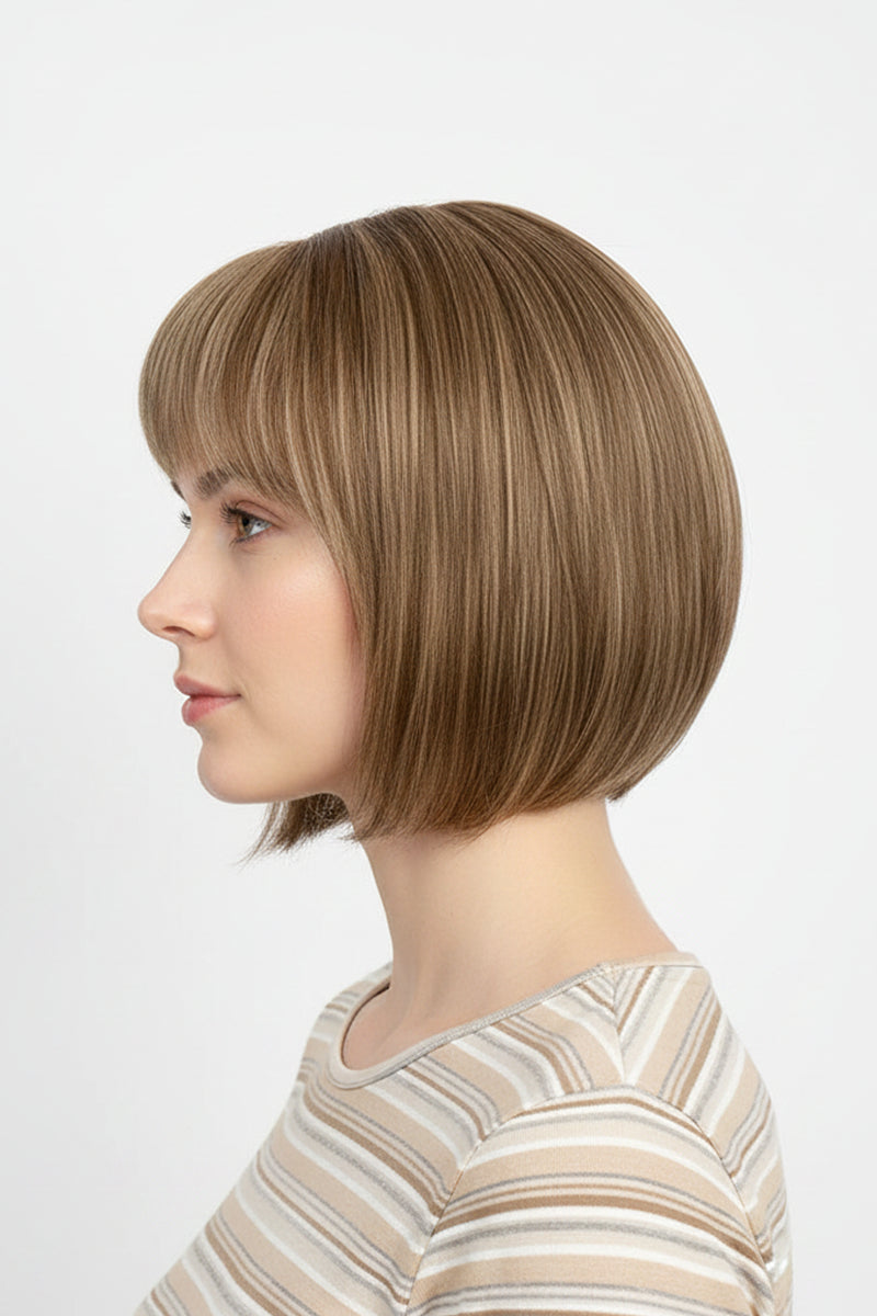 Woman wearing a sandy blonde short bob wig with straight bangs, side profile view, striped top, light gray background