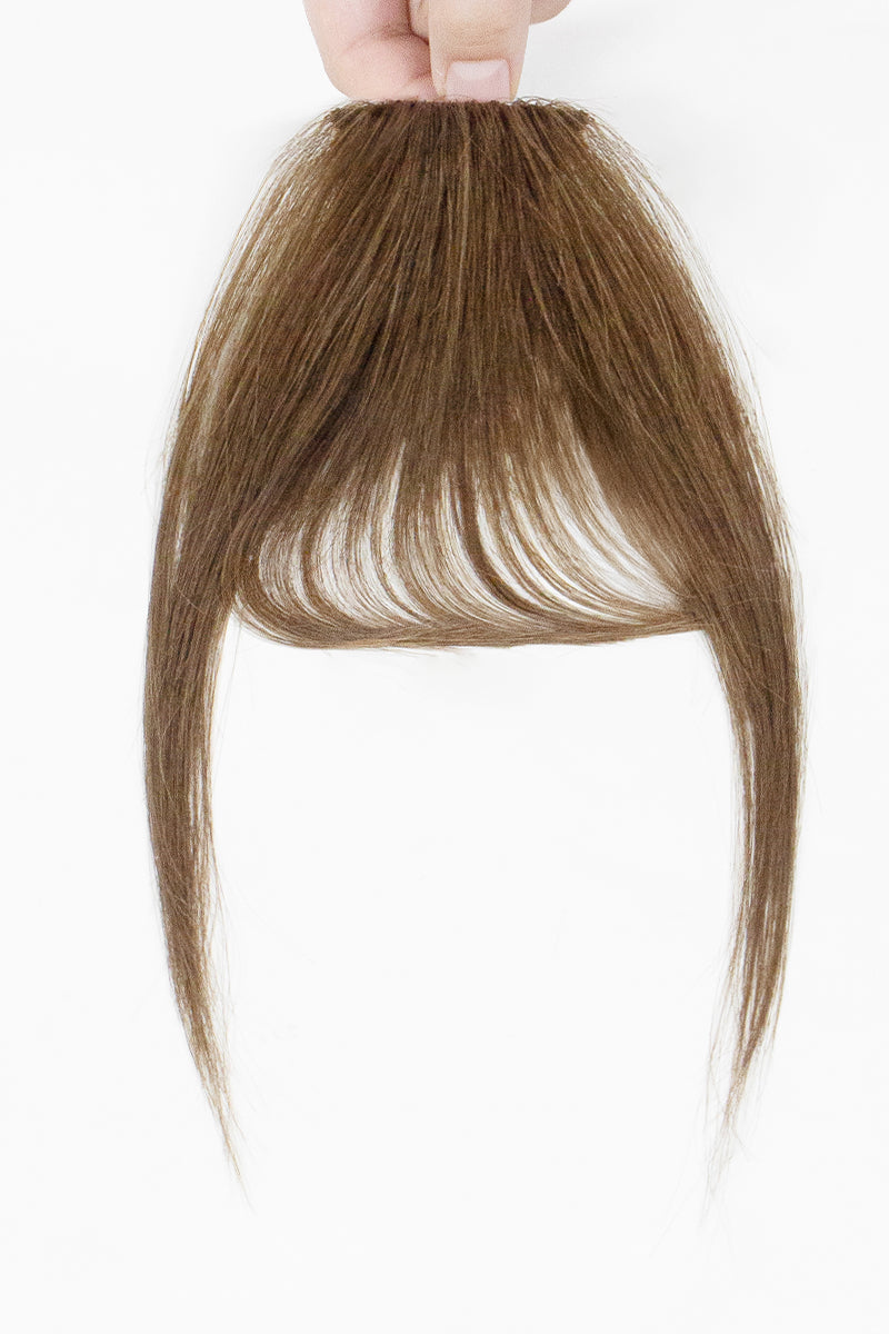 Brown hair bangs held by a hand on a white background