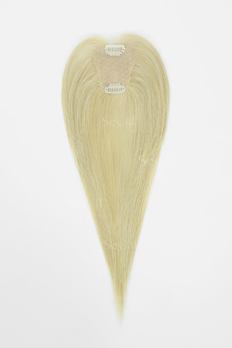 A heart-shaped blonde hair extension piece with a natural-looking beige attachment band, displayed against a plain white background.