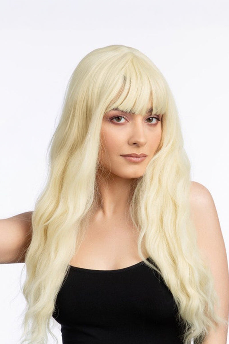 A woman wearing a long, wavy platinum blonde wig with straight-cut bangs, shown against a plain white studio background.