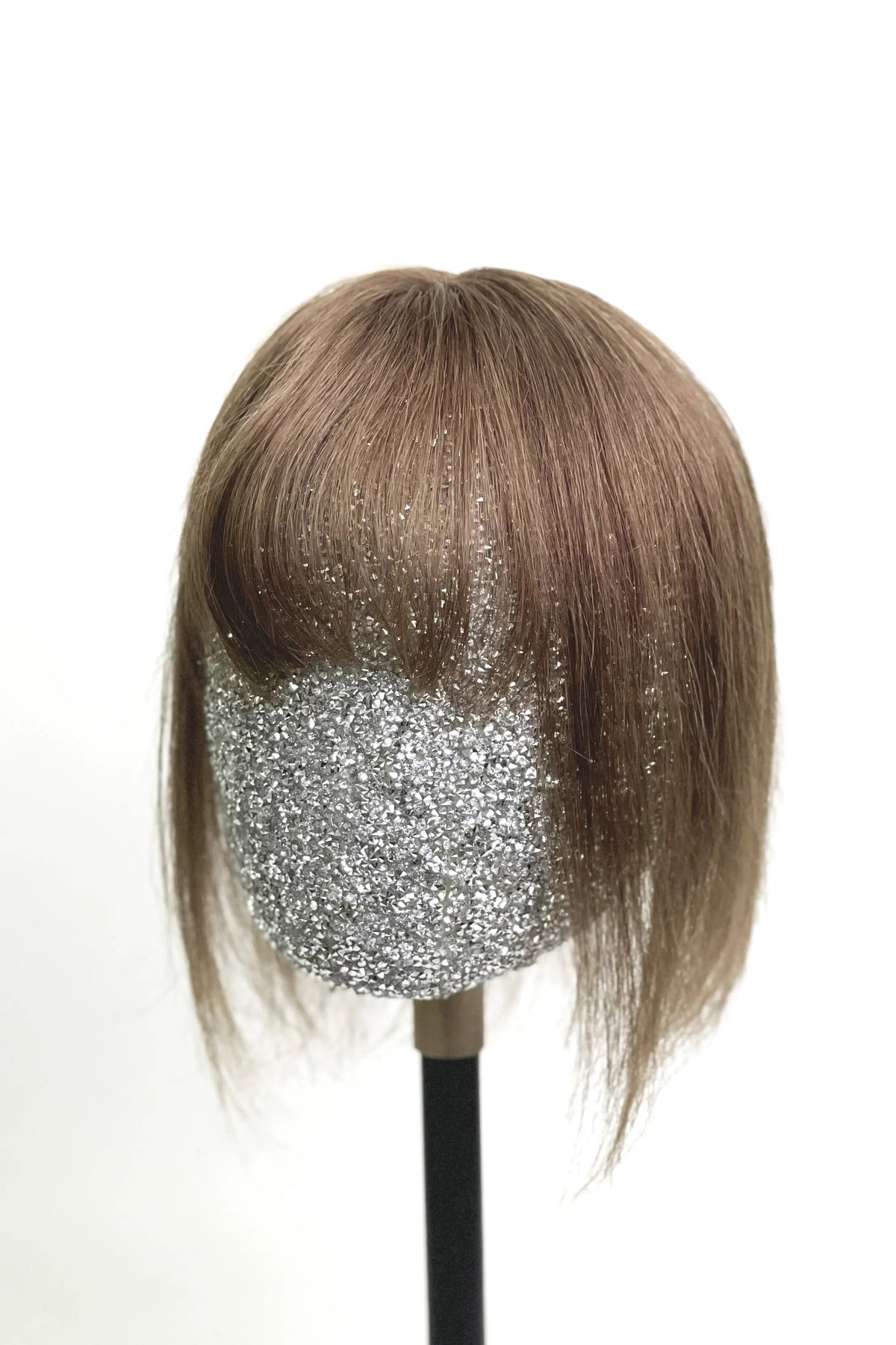 A mannequin head showcasing a medium ash brown human hair topper with bangs.