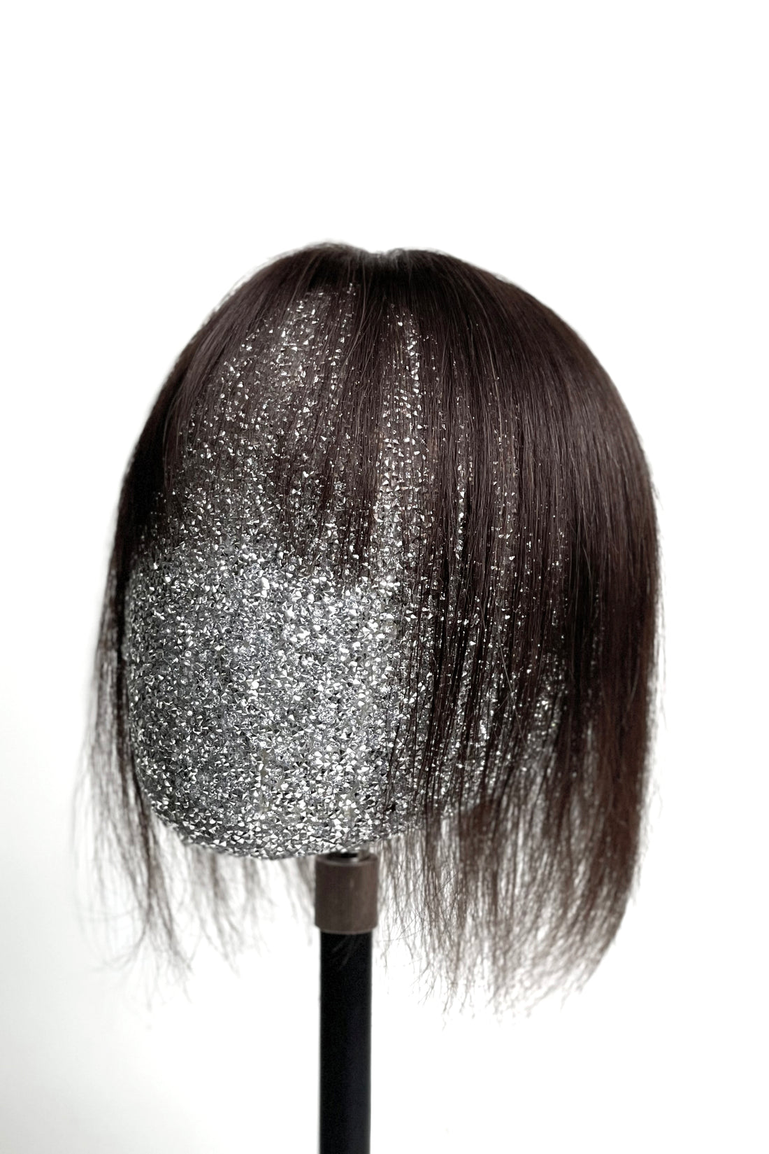 A mannequin head showcasing a dark brown human hair topper with integrated bangs.
