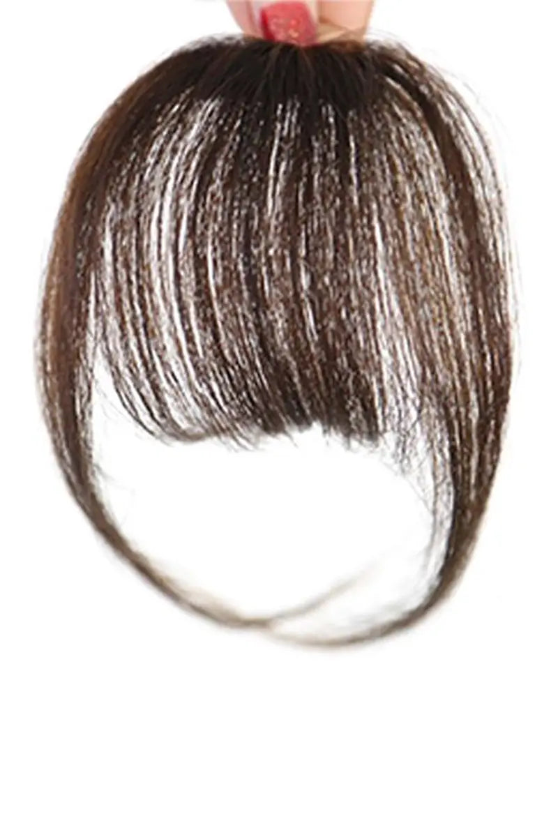 A hand holding a piece of human hair bangs accessory against a white background.