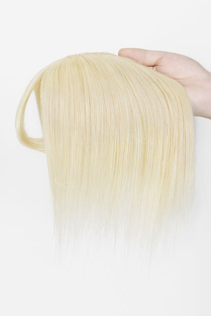 A hand holding a straight, shoulder-length blonde wig against a plain white background.