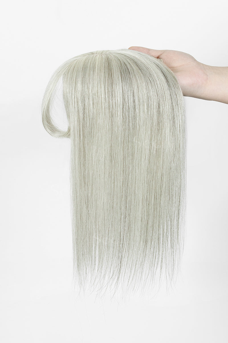 A long, straight wig extension or hairpiece in a very light ash blonde color, held up by a hand against a plain white background.