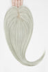 A pale icy ash blonde heart-shaped hair extension held up by a hand against a plain white background.
