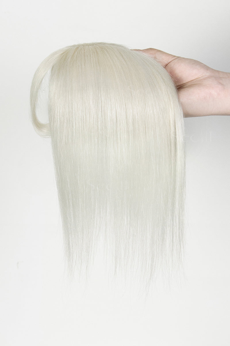 Blonde hair extension held by a hand against a white background