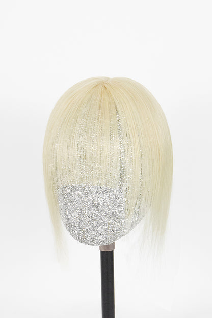 A short, straight blonde wig with bangs displayed on a mannequin head with a black stand against a plain white background.