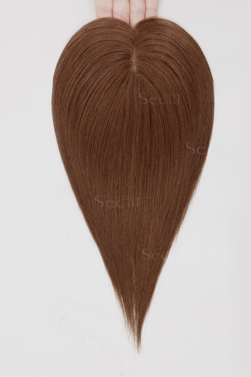 Heart-shaped bundle of brown hair extensions on a white background