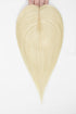 A heart-shaped blonde hair extension or wig piece held at the top by fingers against a plain white background.