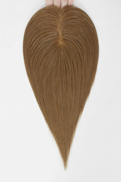 A heart-shaped hair extension or wig piece held at the top by fingers against a plain white background.