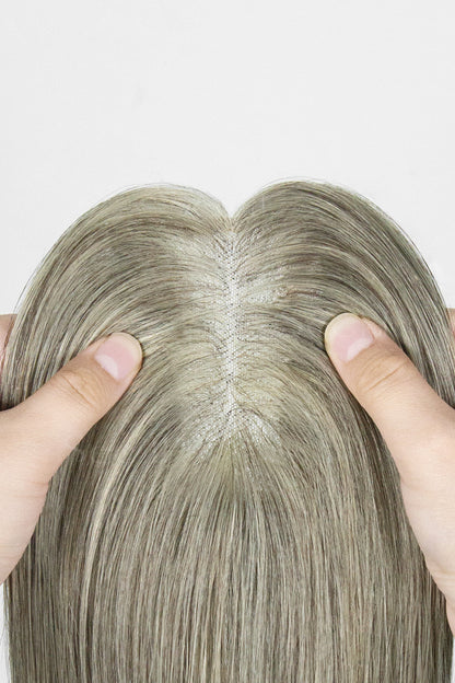 Close-up of a person holding a light brown grey topper with a plain background