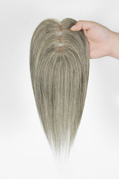 Hairpiece held by a hand against a white background