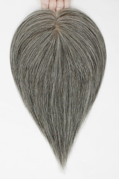 Hand holding a medium grey hair topper with a center part and straight tapered ends.