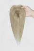 Hand holding a beige blonde hair topper to show the crown, straight texture and tapered ends.