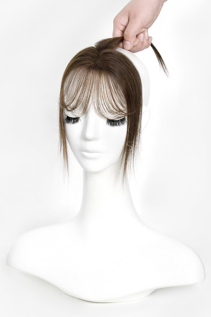 Mannequin head with a hair topper being adjusted on a white background