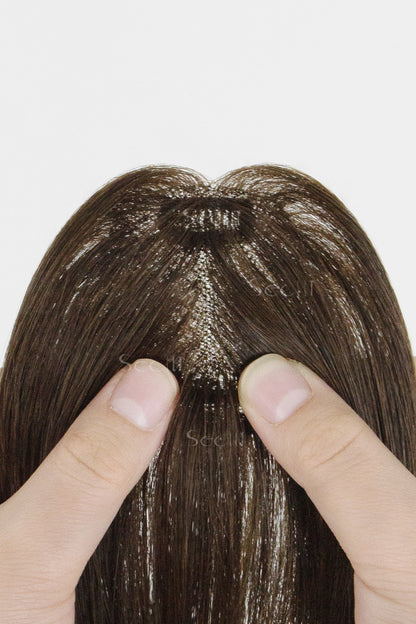 Brown hair topper held between two fingers on a white background
