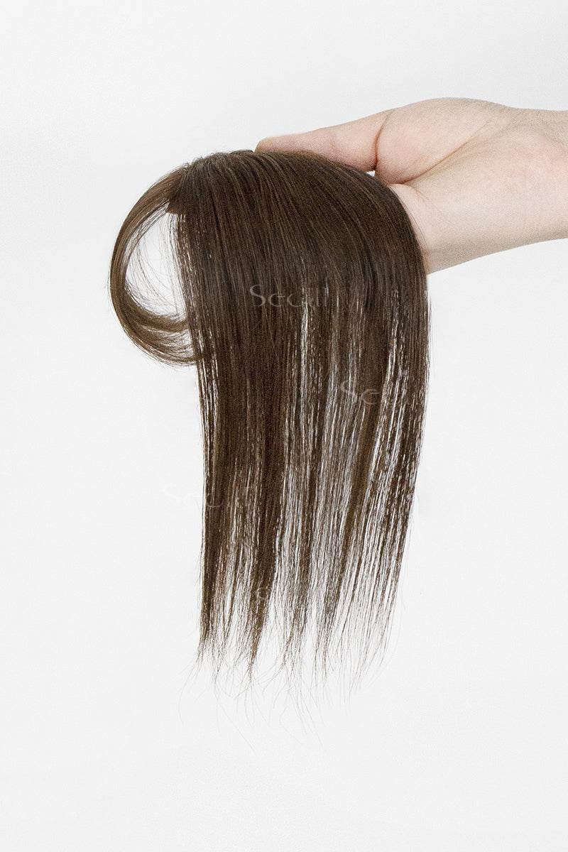 Brown hair topper held by a hand on a white background