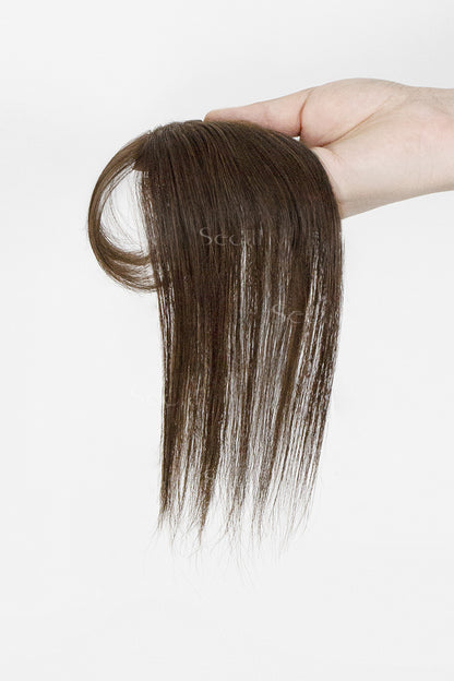 Brown hair topper held by a hand on a white background