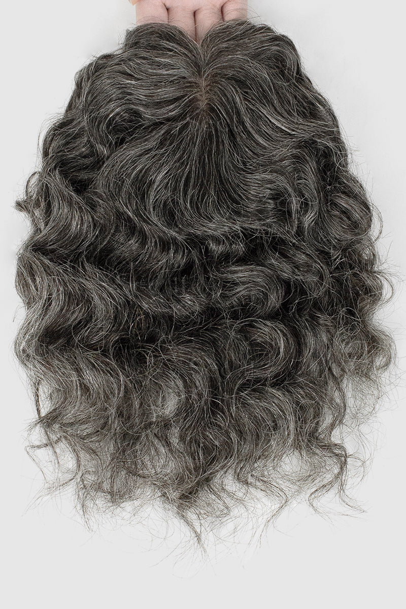 Curly gray hair extension held by hands on a white background