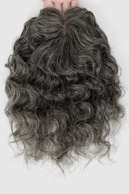 Curly gray hair extension held by hands on a white background