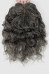 Curly gray hair extension held by hands on a white background