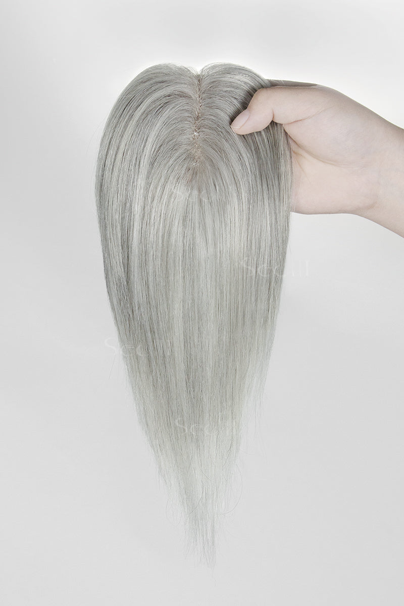 Light Gray hair topper held by a hand against a white background