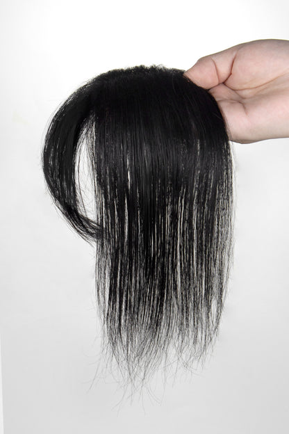 Black hair extension held by a hand against a white background