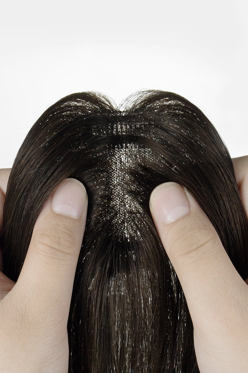Close-up of a hair Topper patch with fingers holding it against a white background