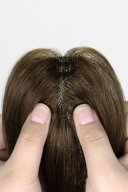 Close-up of a topper being held between fingers on a white background