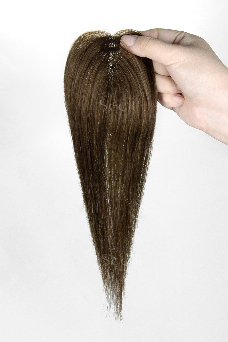 Hair topper held by a hand against a white background