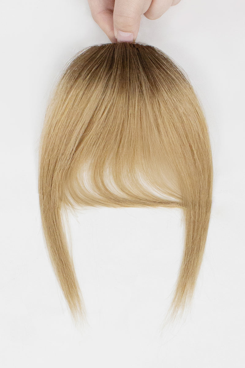 Blonde hair topper held by a hand on a white background