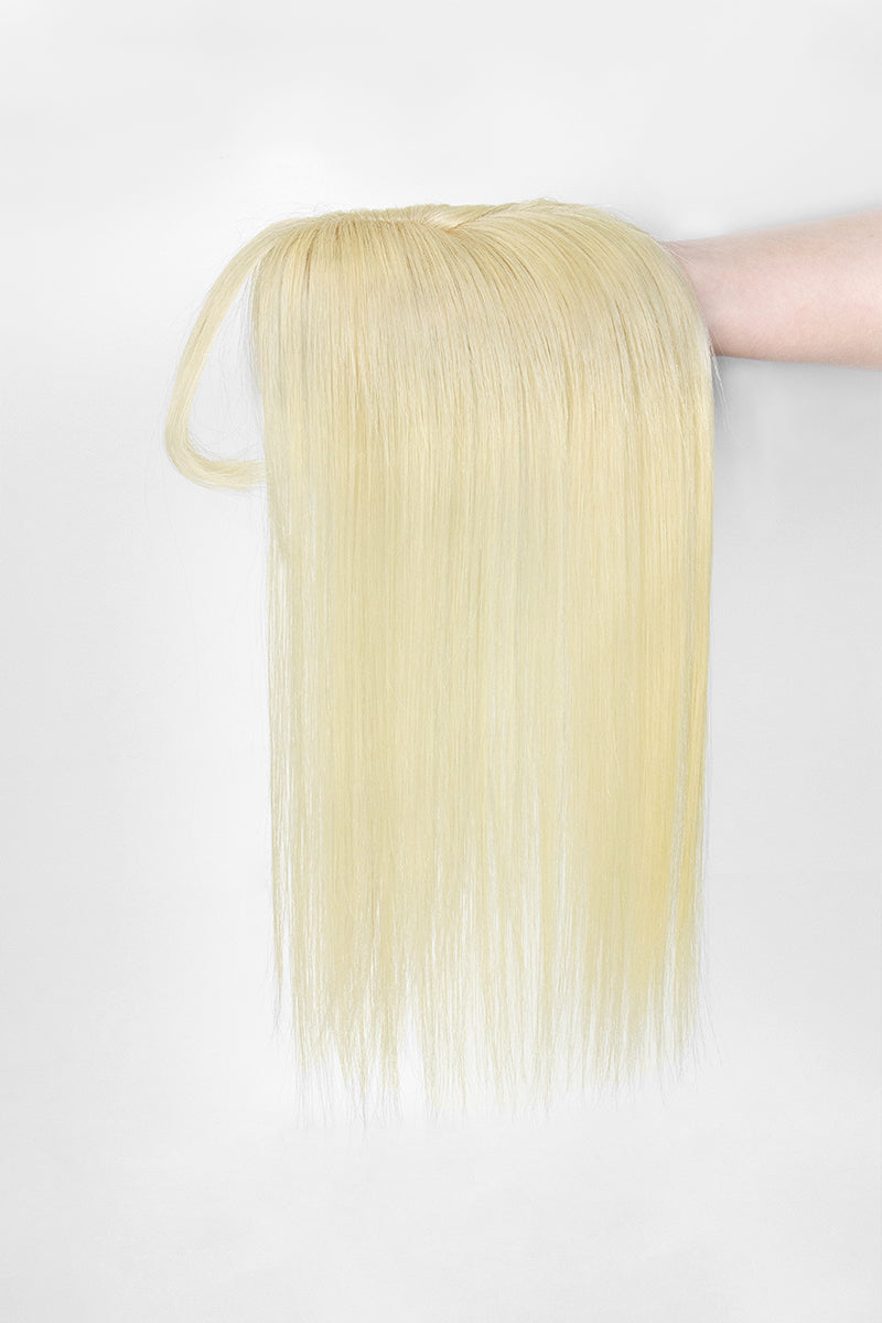 Hera Human Hair and Handmade Topper with Bangs held by a hand on a white background