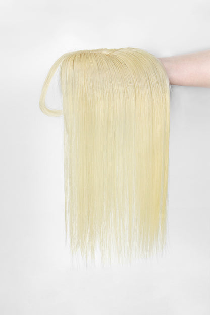 Hera Human Hair and Handmade Topper with Bangs held by a hand on a white background